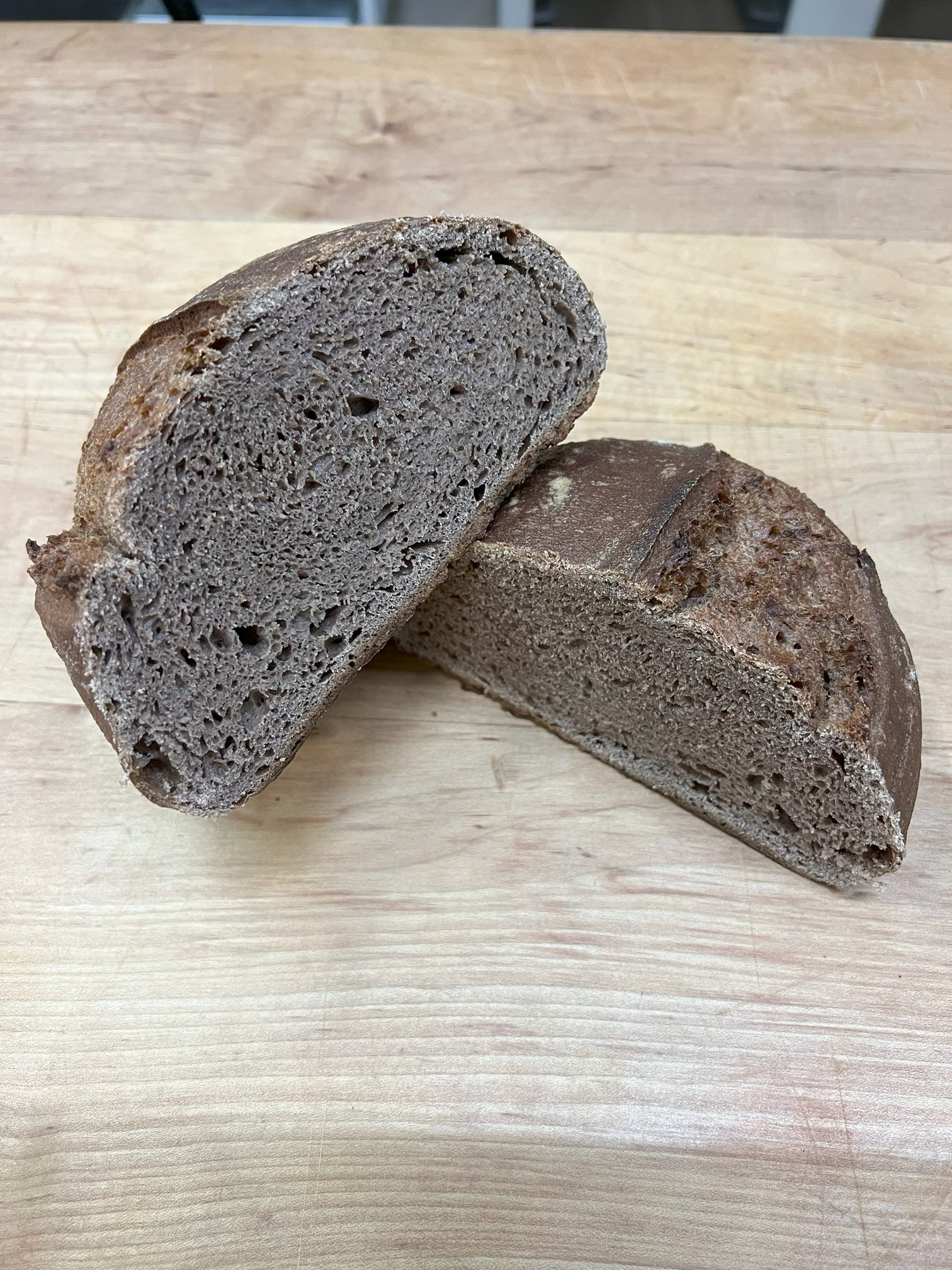 A loaf of bread is sliced in half with one piece displayed on top of the other showing the top and inside of the bread.